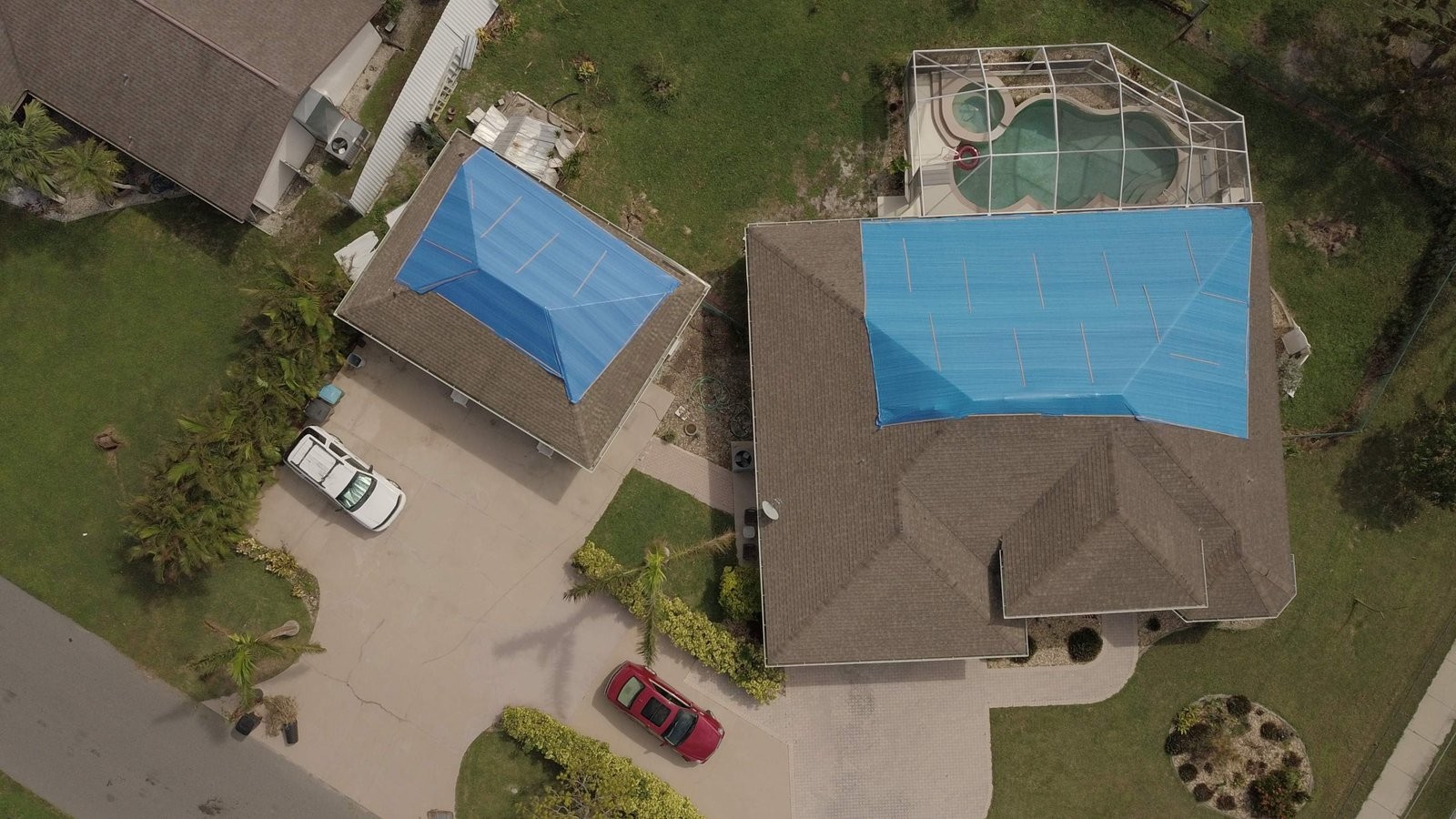Aerial view of two Cape Coral homes with blue FarFan storm tarps fastened over their roofs