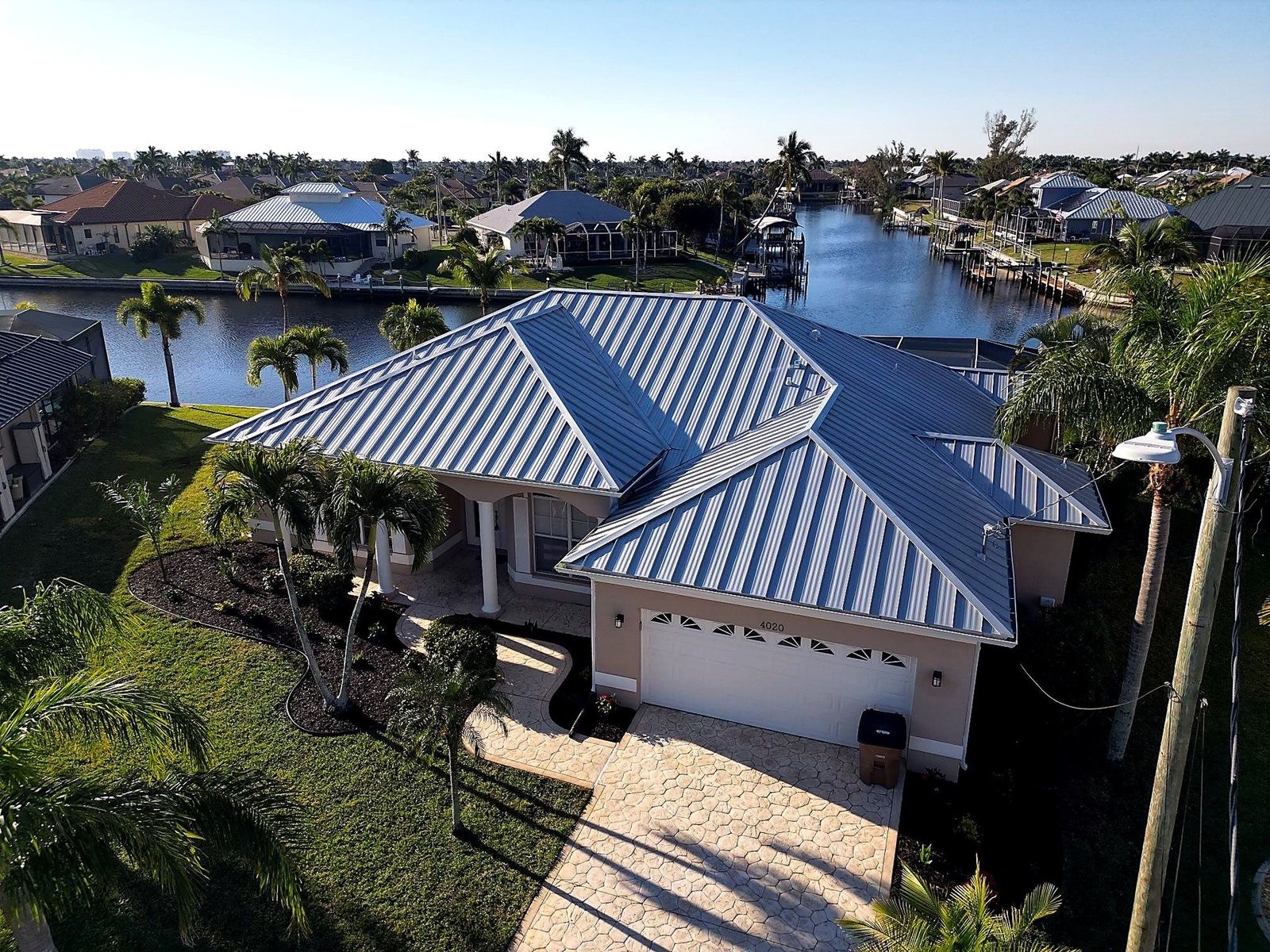 Aerial view of a Cape Coral canal-front home with a new standing seam metal roof by FarFan